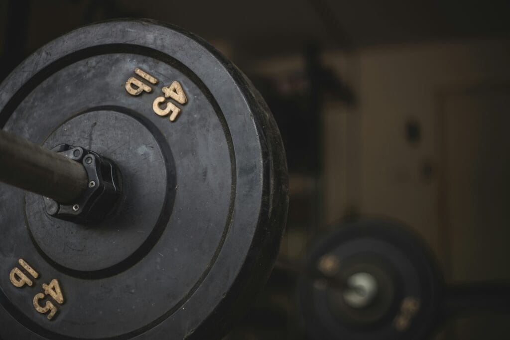 Photo of a barbell resting on the floor with weights on it.